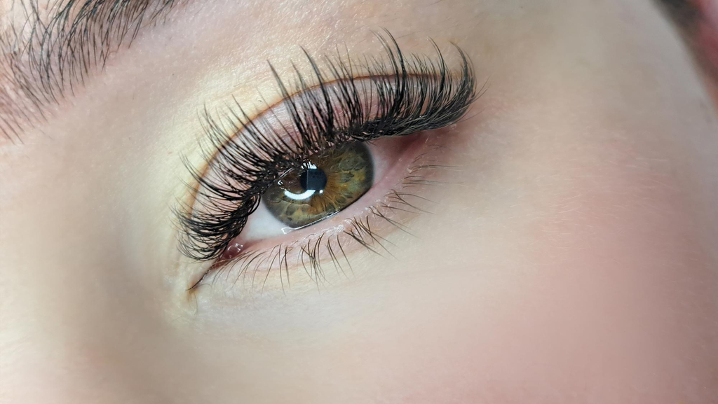 A woman with brown and green eyes with volume eyelash extensions. The make up is very natural and the eyelashes are prominent and full. These are volume eyelash extensions.