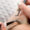 Eyelash extension procedure in process. There is a close up of a woman's face with another woman with white nails and tweezers putting the eyelash in place.