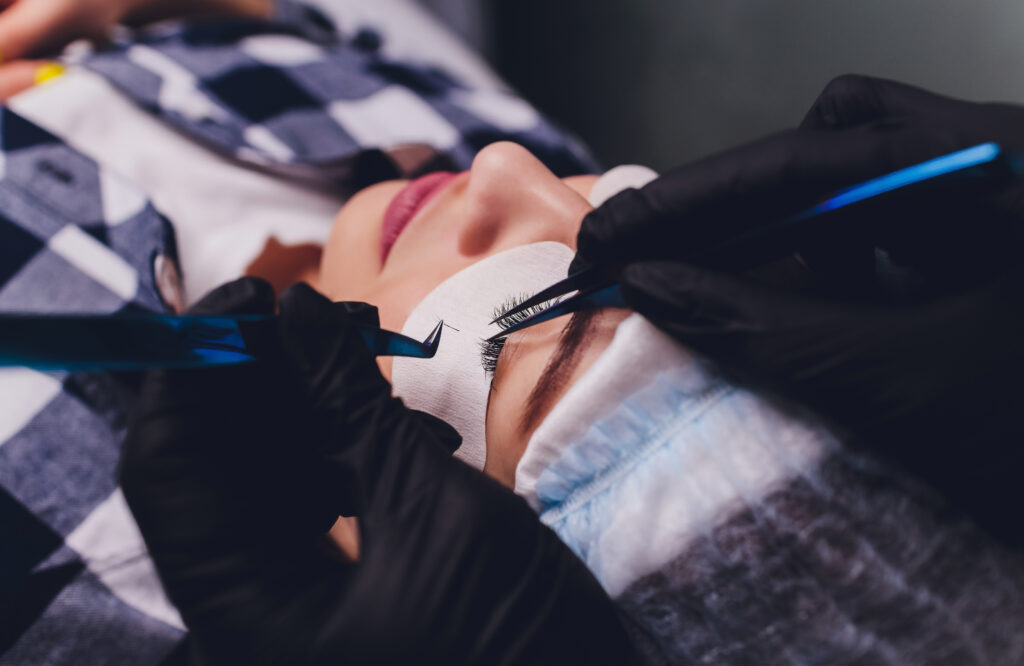 A lash tech with black gloves applying lash extensions to a client