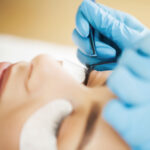 A close up of a women having eyelash extensions applied.