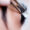 Close-up of an eyelash extension procedure showing a technician applying individual lash extensions to a woman's natural lashes using precision tweezers, with an under-eye pad in place for protection.