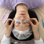 The top view of a woman getting eyelash extensions, she is having eyelash patches put on.