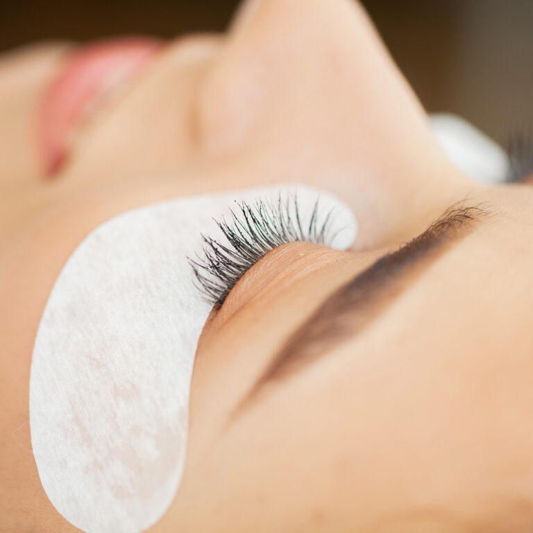 Close up of eyelash extensions and a woman lying down.