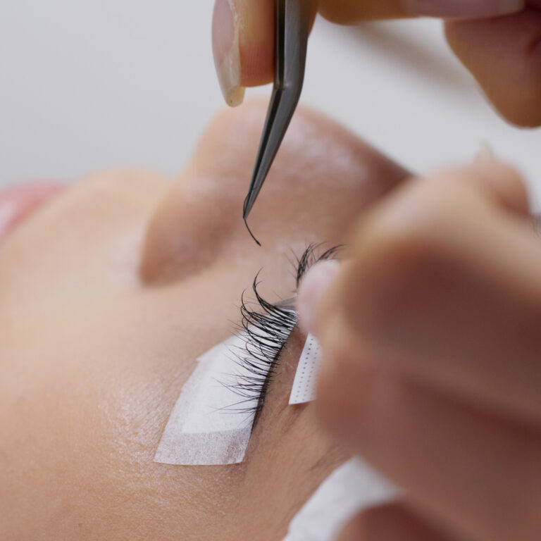 Woman having classic eyelash extension in beauty salon