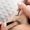 Eyelash extension procedure in process. There is a close up of a woman's face with another woman with white nails and tweezers putting the eyelash in place.