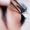 Close-up of an eyelash extension procedure showing a technician applying individual lash extensions to a woman's natural lashes using precision tweezers, with an under-eye pad in place for protection.