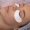 side view of a woman wearing under-eye patches with natural eyelash extensions.