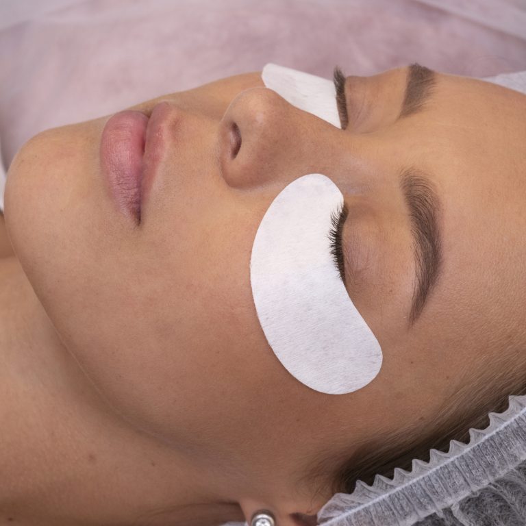 side view of a woman wearing under-eye patches with natural eyelash extensions.
